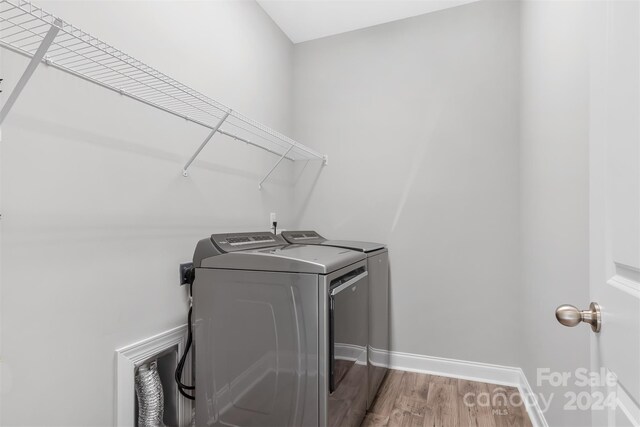 clothes washing area featuring independent washer and dryer and light hardwood / wood-style floors