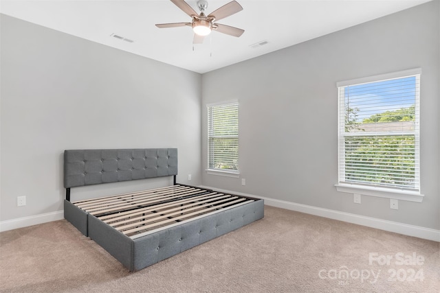 carpeted bedroom with ceiling fan and multiple windows