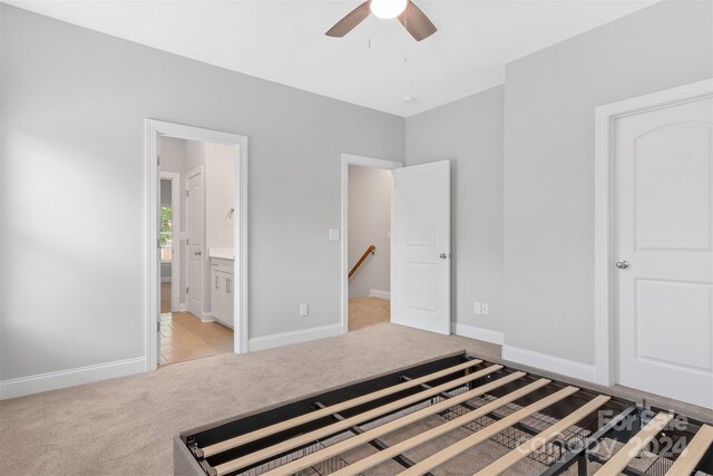 unfurnished bedroom with ceiling fan, light carpet, and ensuite bath