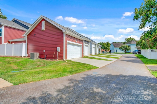 view of side of home featuring a garage, central AC unit, and a lawn