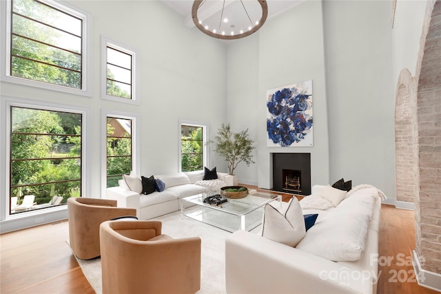 living room with a towering ceiling, wood-type flooring, and a notable chandelier