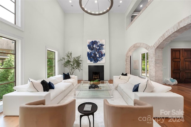 living room featuring hardwood / wood-style flooring, a wealth of natural light, a chandelier, and a high ceiling