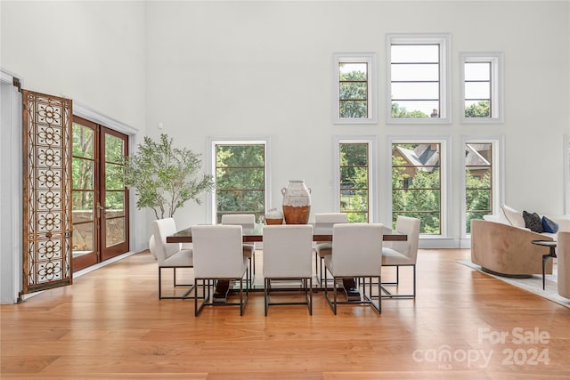 dining space featuring a towering ceiling and light wood-type flooring