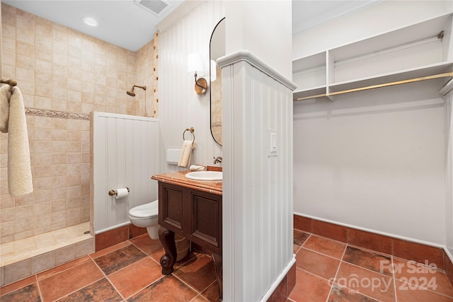 bathroom with crown molding, vanity, toilet, and a shower