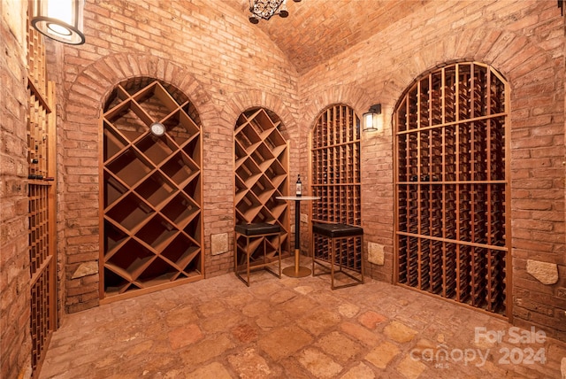 wine room with brick wall and vaulted ceiling