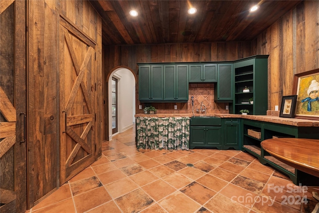 kitchen featuring wooden ceiling, sink, green cabinetry, and wooden walls