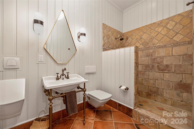 bathroom with crown molding, toilet, tiled shower, and tile patterned floors