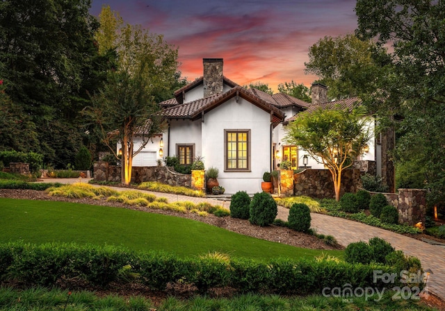 mediterranean / spanish home with a lawn and a garage