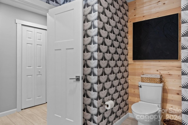 bathroom with toilet and wood walls