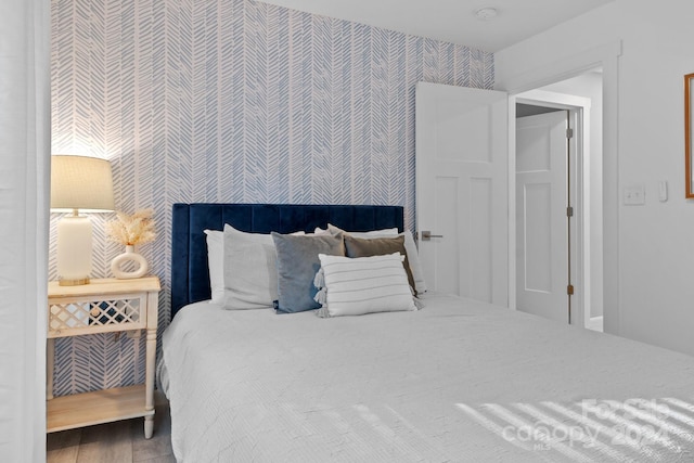 bedroom featuring wood finished floors and wallpapered walls