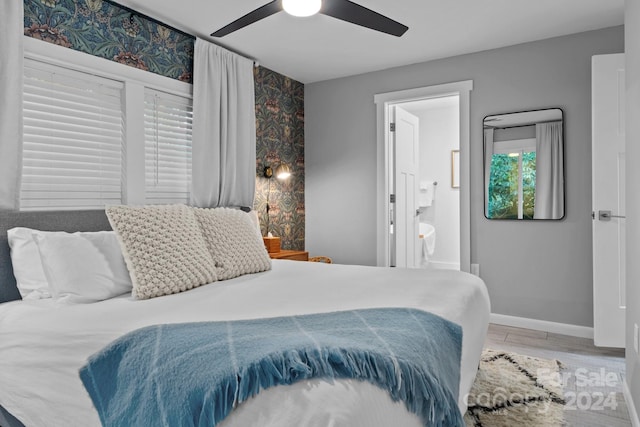 bedroom featuring ceiling fan, ensuite bath, baseboards, and wood finished floors