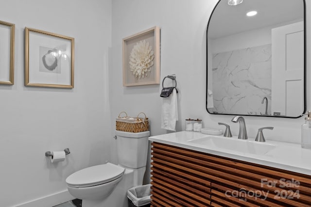 bathroom featuring baseboards, toilet, and vanity