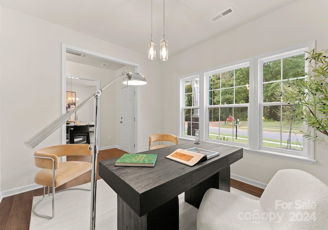 dining space with a wealth of natural light, dark wood-style flooring, visible vents, and an inviting chandelier