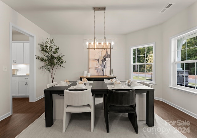 dining room with baseboards, a notable chandelier, visible vents, and wood finished floors