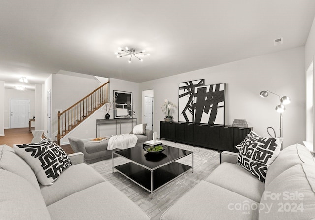 living room featuring stairs, visible vents, and wood finished floors