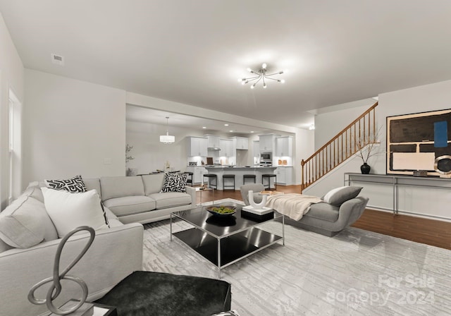 6034 Jepson Ct, Charlotte, NC 28214 - living room featuring stairway, visible vents, an inviting chandelier, and wood finished floors
