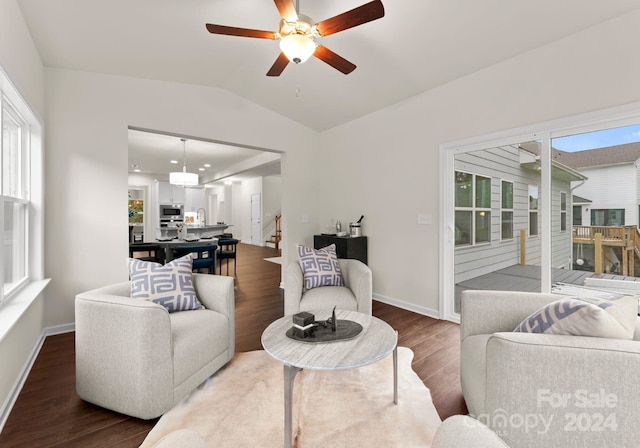 living room with a healthy amount of sunlight, baseboards, vaulted ceiling, and wood finished floors