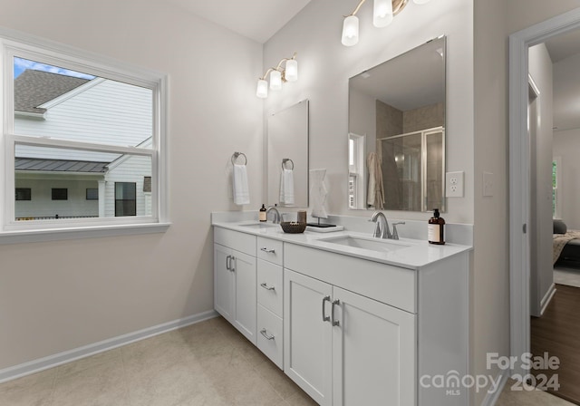 ensuite bathroom with a stall shower, double vanity, a sink, and ensuite bathroom