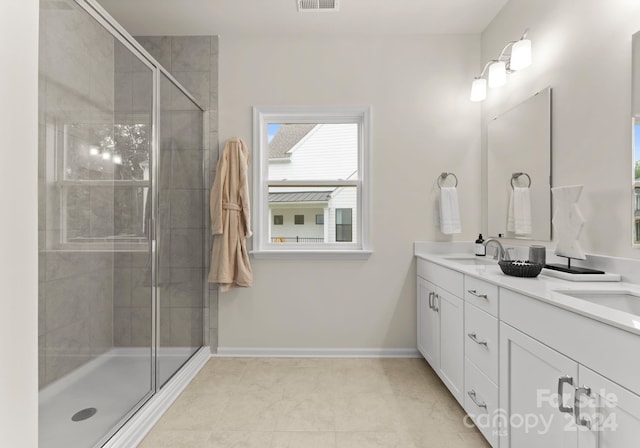 full bathroom featuring double vanity, visible vents, a sink, a shower stall, and baseboards