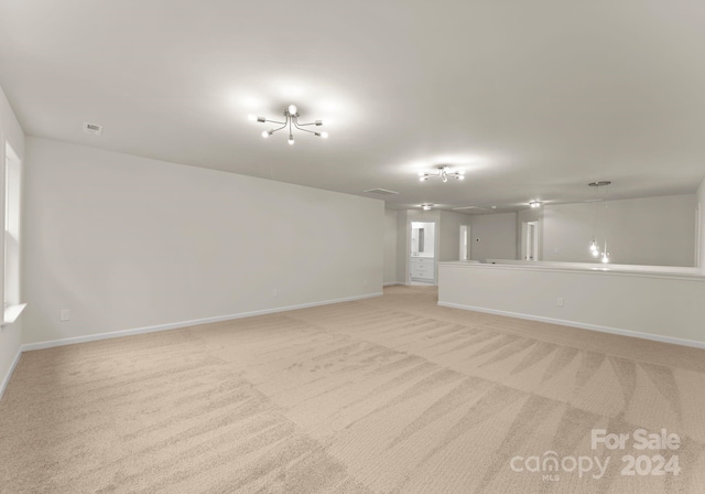 spare room featuring light colored carpet, visible vents, and baseboards