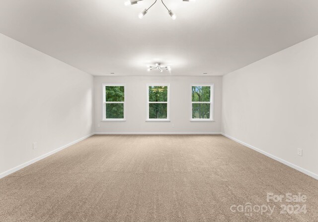 unfurnished room with light colored carpet and baseboards