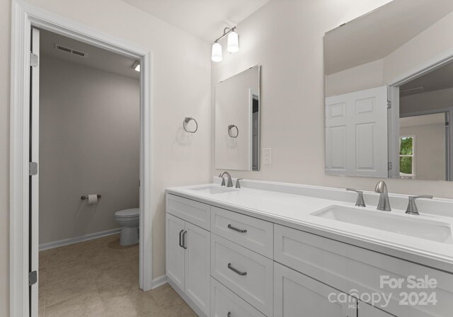 full bath featuring double vanity, tile patterned flooring, a sink, and toilet