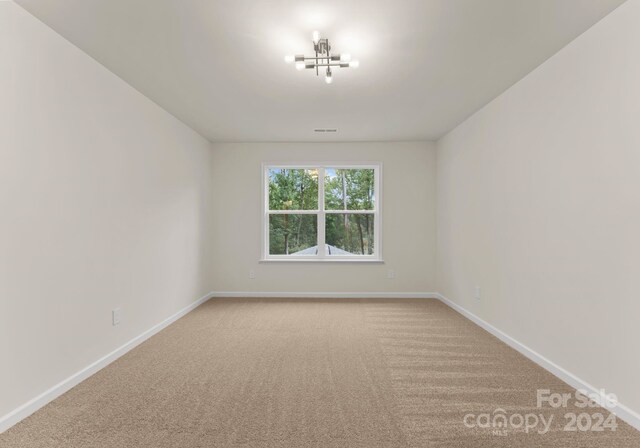 unfurnished room featuring carpet floors, visible vents, and baseboards