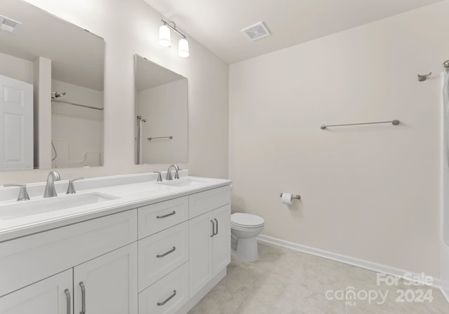 bathroom with toilet, double vanity, visible vents, and a sink