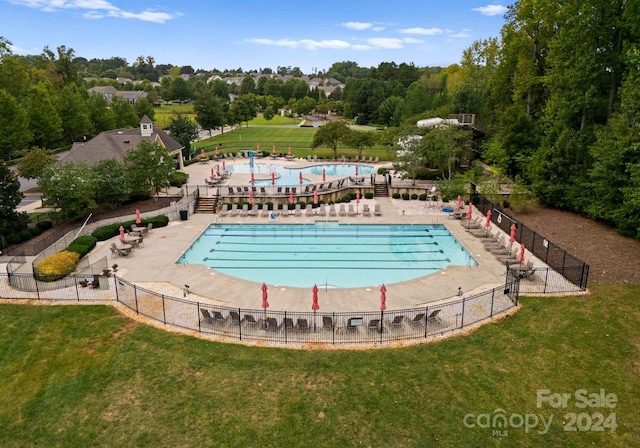 pool featuring fence, a patio, and a yard