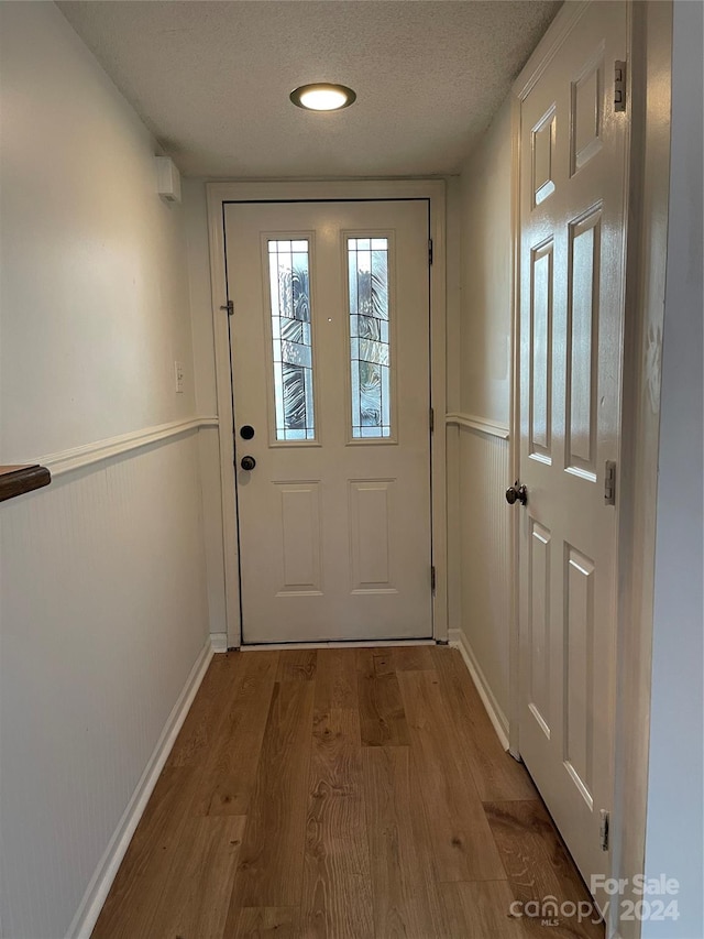 doorway to outside with a textured ceiling and wood-type flooring