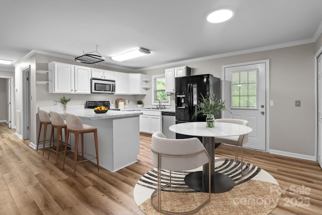 kitchen featuring black appliances, sink, ornamental molding, light hardwood / wood-style floors, and white cabinetry