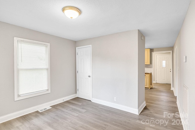 unfurnished room featuring visible vents, light wood finished floors, and baseboards