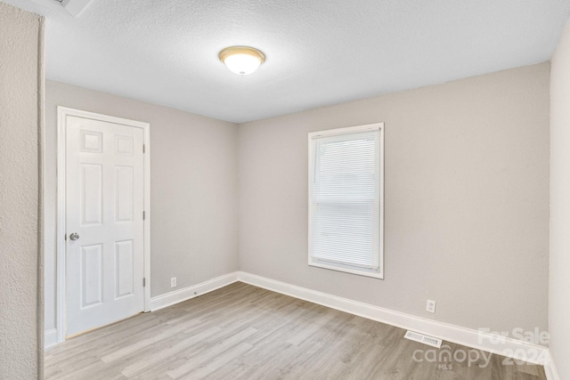 spare room featuring light hardwood / wood-style flooring and a textured ceiling