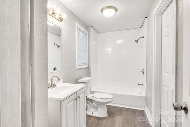 full bathroom with vanity, a textured ceiling, tiled shower / bath, wood-type flooring, and toilet