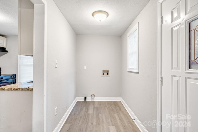 laundry room featuring light hardwood / wood-style flooring, washer hookup, and a textured ceiling