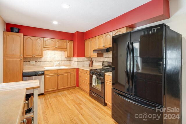 kitchen featuring black appliances, sink, light hardwood / wood-style flooring, and tasteful backsplash