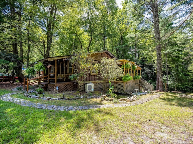 rear view of house with a wooded view, a lawn, and ac unit