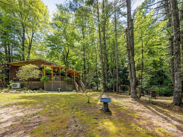 view of yard with ac unit, a view of trees, a wooden deck, and stairway
