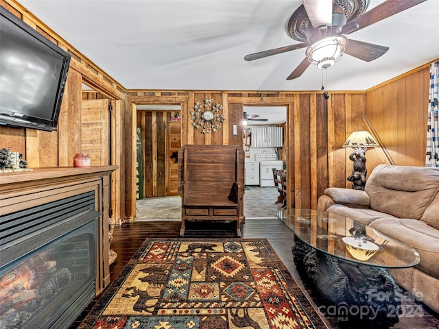 living room with ceiling fan, wooden walls, and dark wood-type flooring