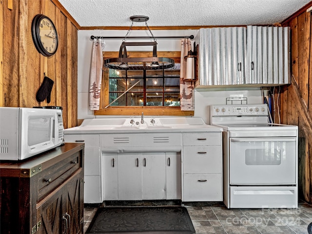 kitchen featuring white cabinets, wooden walls, sink, and white appliances