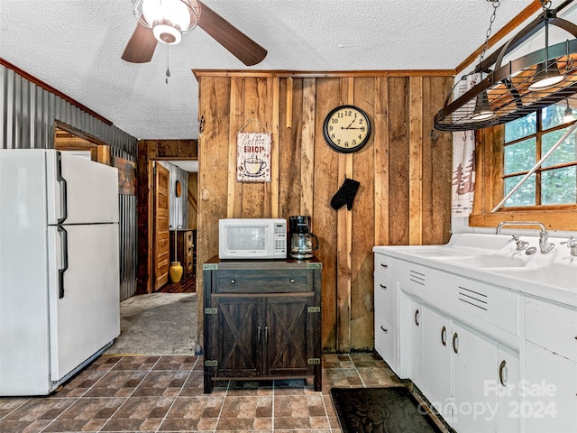 kitchen with ceiling fan, white appliances, wooden walls, and white cabinetry