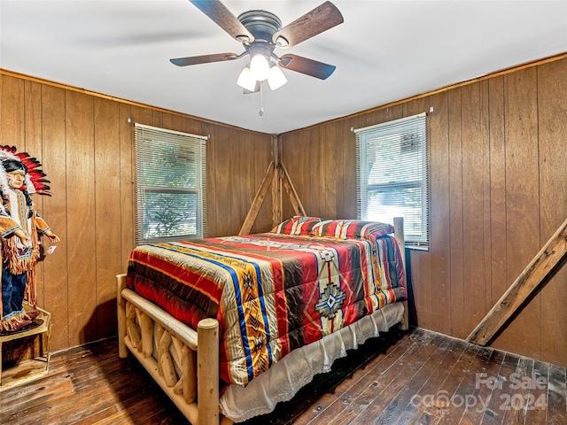 bedroom featuring ceiling fan, wooden walls, and wood-type flooring