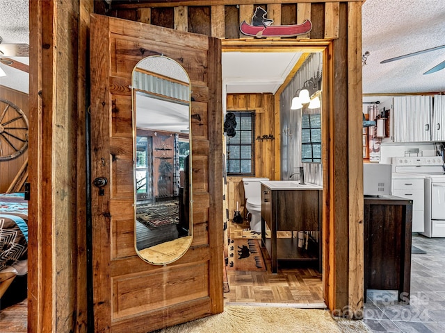 interior space featuring washer and clothes dryer, a textured ceiling, wood walls, and light parquet floors