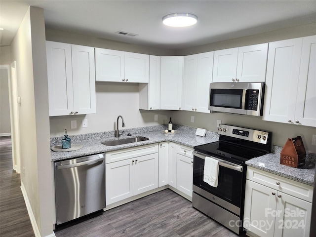 kitchen featuring visible vents, dark wood-type flooring, stainless steel appliances, white cabinetry, and a sink