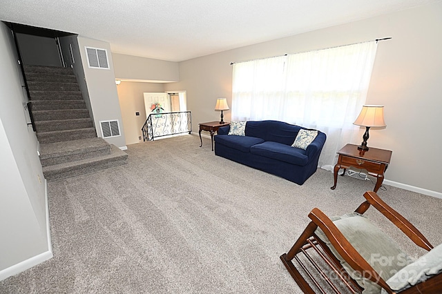 living room featuring visible vents, a textured ceiling, carpet flooring, and stairs