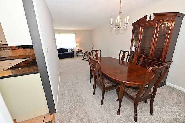 dining room featuring a textured ceiling, baseboards, a notable chandelier, and light colored carpet