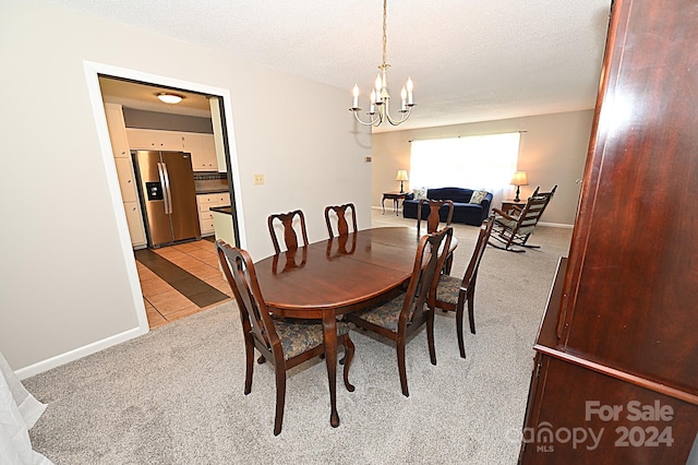 dining room featuring light carpet, light tile patterned floors, baseboards, a textured ceiling, and a notable chandelier