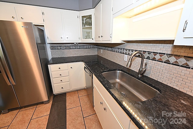 kitchen with decorative backsplash, glass insert cabinets, stainless steel appliances, white cabinetry, and a sink