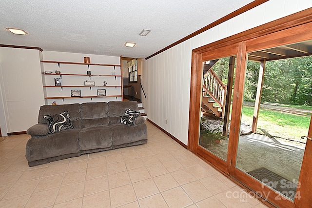 living area with a textured ceiling, wood walls, stairway, and crown molding