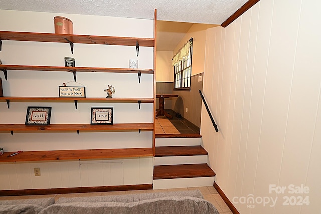 stairway with tile patterned flooring and a textured ceiling